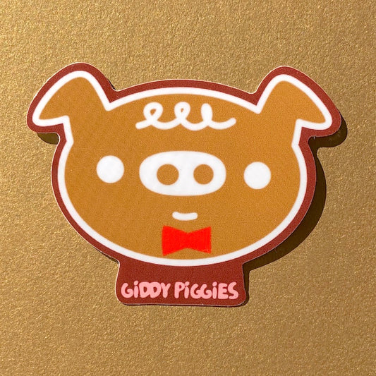 A glossy vinyl sticker of a cartoon pig with a bow tie and the text 'Giddy Piggies'.